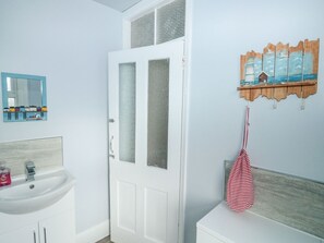 A bathroom with a white sink, a mirror, and a frosted glass door. - Dunholme House (Teignmouth)