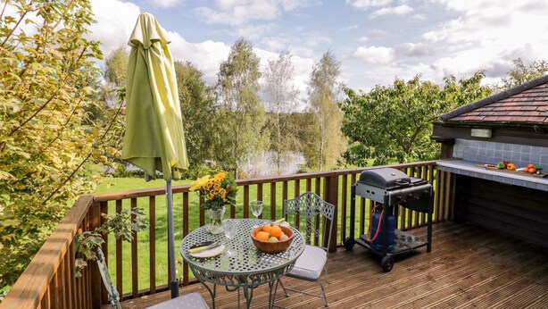 A deck with a grill, a table with a bowl of fruit, and a chair. - The Stilehouse Apartment (Worcester)