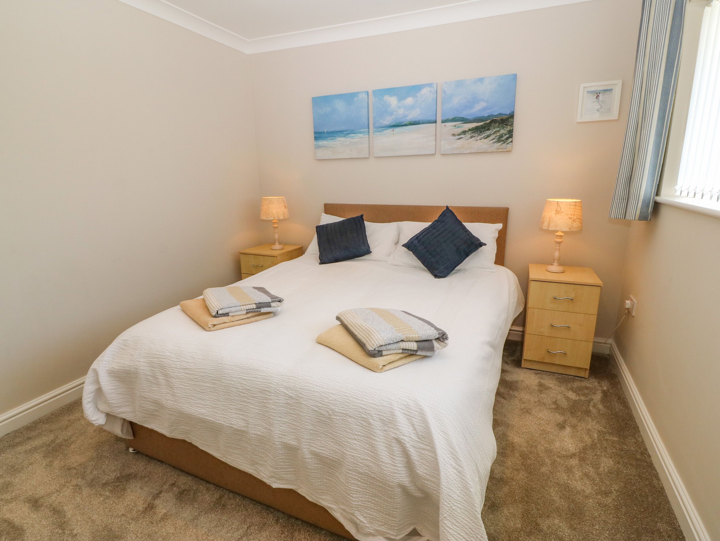 A neatly arranged bedroom with a bed, two bedside tables, and a wall-mounted painting.