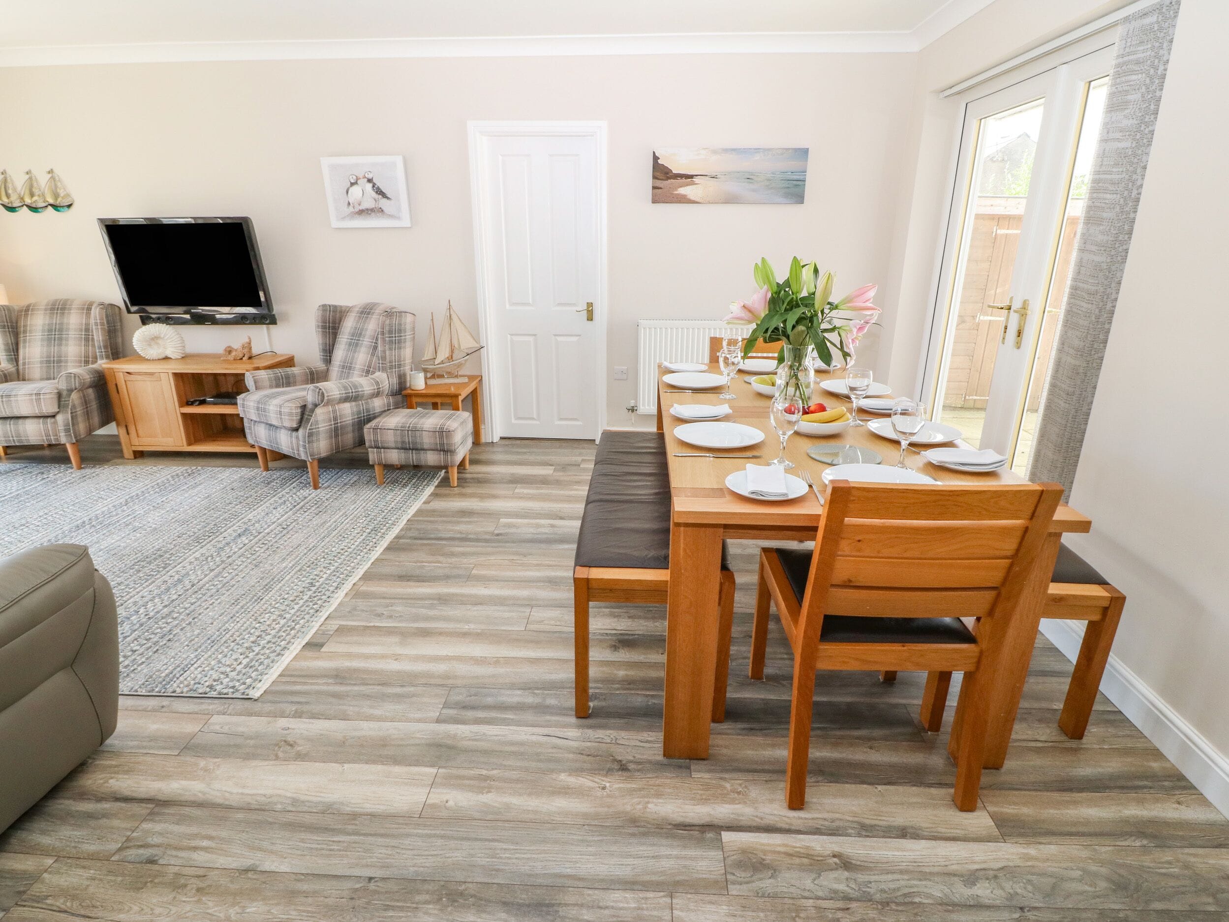 A living room with a dining area, a TV, and a door.
