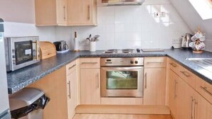 Una cocina compacta con microondas, estufa, horno y armarios de madera.