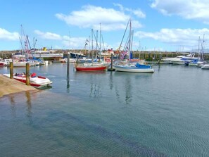 A marina with various boats docked, a waterfront view, and a distant shoreline. - Carisbrooke House, Apartment 6 (Scarborough)