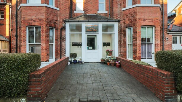A red brick building with a white entrance and a small porch. There are potted plants on the porch. - Carisbrooke House, Apartment 6 (Scarborough)