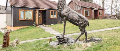 A deer sculpture in a grassy area with a house in the background.