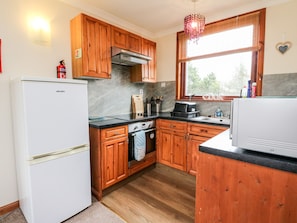 A compact kitchen with wooden cabinets, a stove, and a refrigerator.