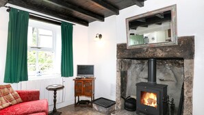 En hyggelig stue med pejs, fjernsyn og en behagelig rød sofa.