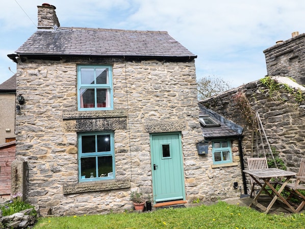 A stone house with a blue door and windows, a small garden, and a wooden table and chairs outside. - Sunny Bank View (Hope Valley)