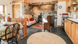 Une cuisine chaleureuse avec un mur en pierre, des meubles en bois et un tapis rouge.