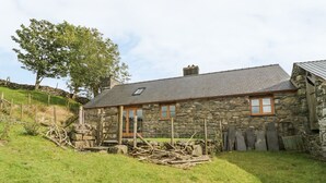 Une maison en pierre avec un toit en pente, une porte en bois et une petite fenêtre.