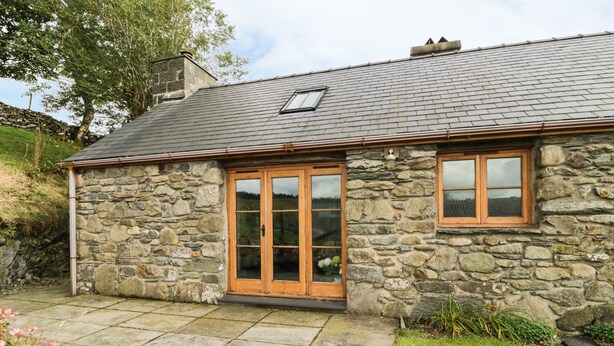 Une maison en pierre avec un patio carrelé et une porte en bois.