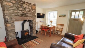 Una sala de estar acogedora con chimenea de piedra, sofás de cuero, un comedor y televisión.