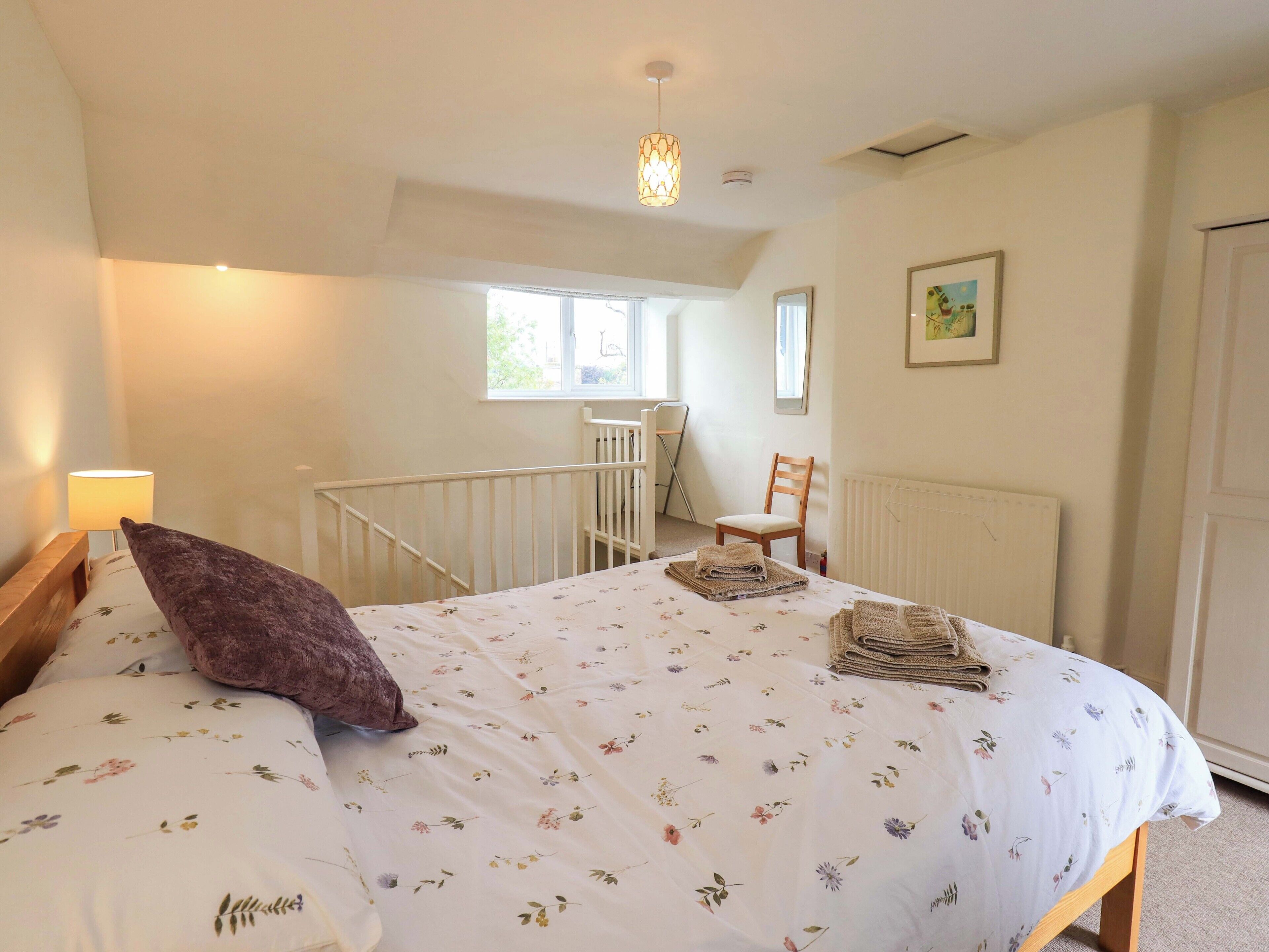 A bedroom with a bed, a chair, a radiator, and a window.
