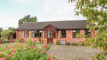 Stunning brick home with a charming entrance, surrounded by a beautifully maintained garden and paved driveway.