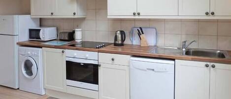 A modern kitchen with white cabinets, a microwave, a toaster, a kettle, and a dishwasher.