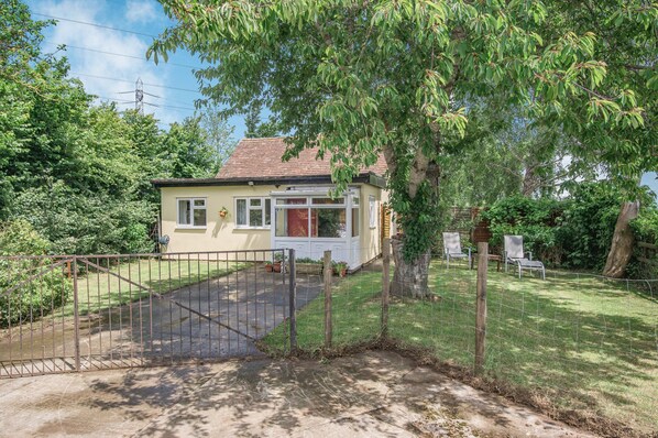 A single-story house with a front yard, a gated driveway, and a tree providing shade. - Sunshine Lodge (Bridgwater)