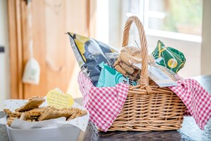 A wicker basket filled with various food items, including biscuits and cookies, placed on a table with a checkered cloth. - Sunshine Lodge (Bridgwater)