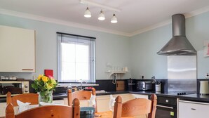A modern kitchen with wooden chairs, a dining table, and a large window.