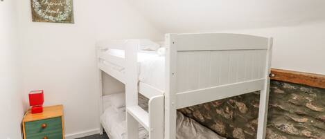 A bunk bed room with a small wooden nightstand and a framed sign on the wall.