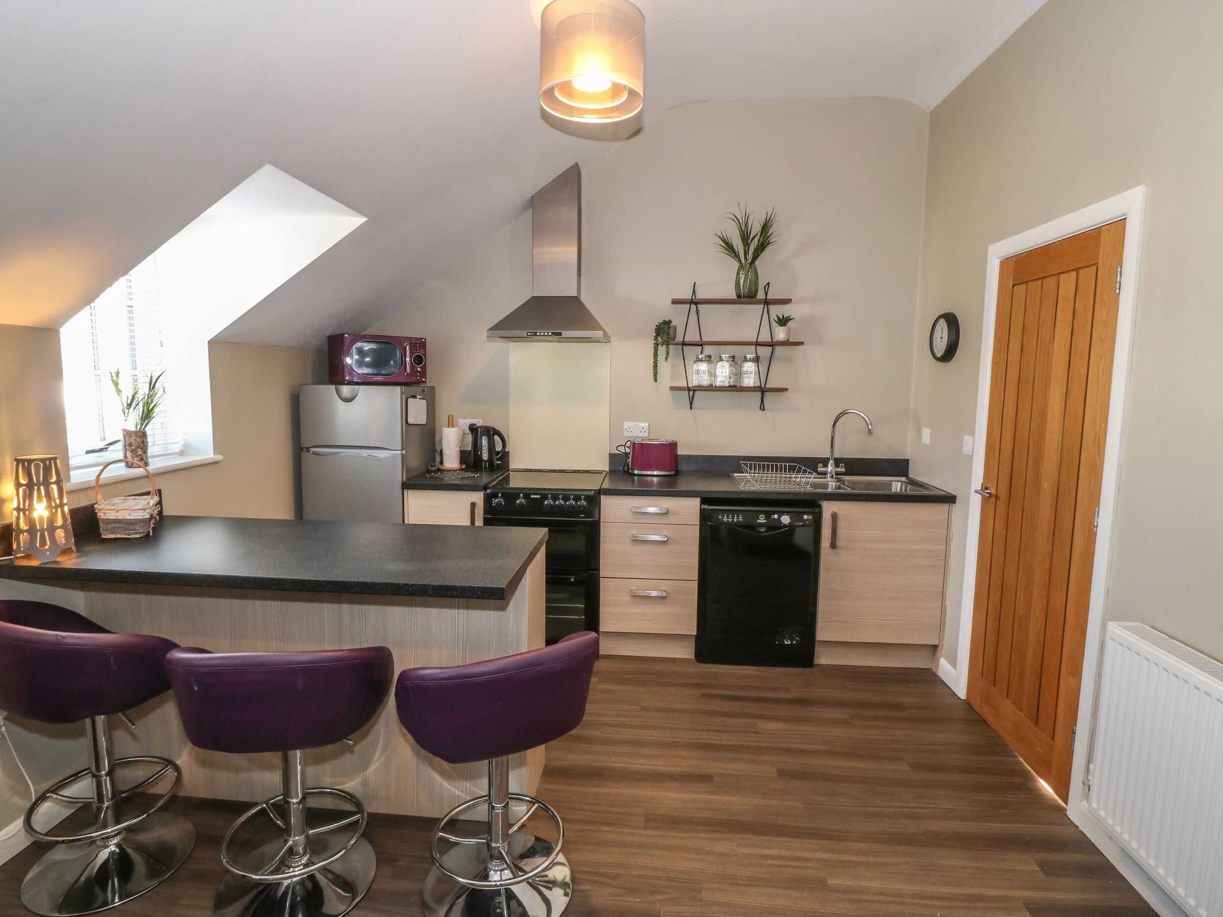 A modern kitchen with a central island, bar stools, a microwave, a refrigerator, a stove, and a dishwasher.