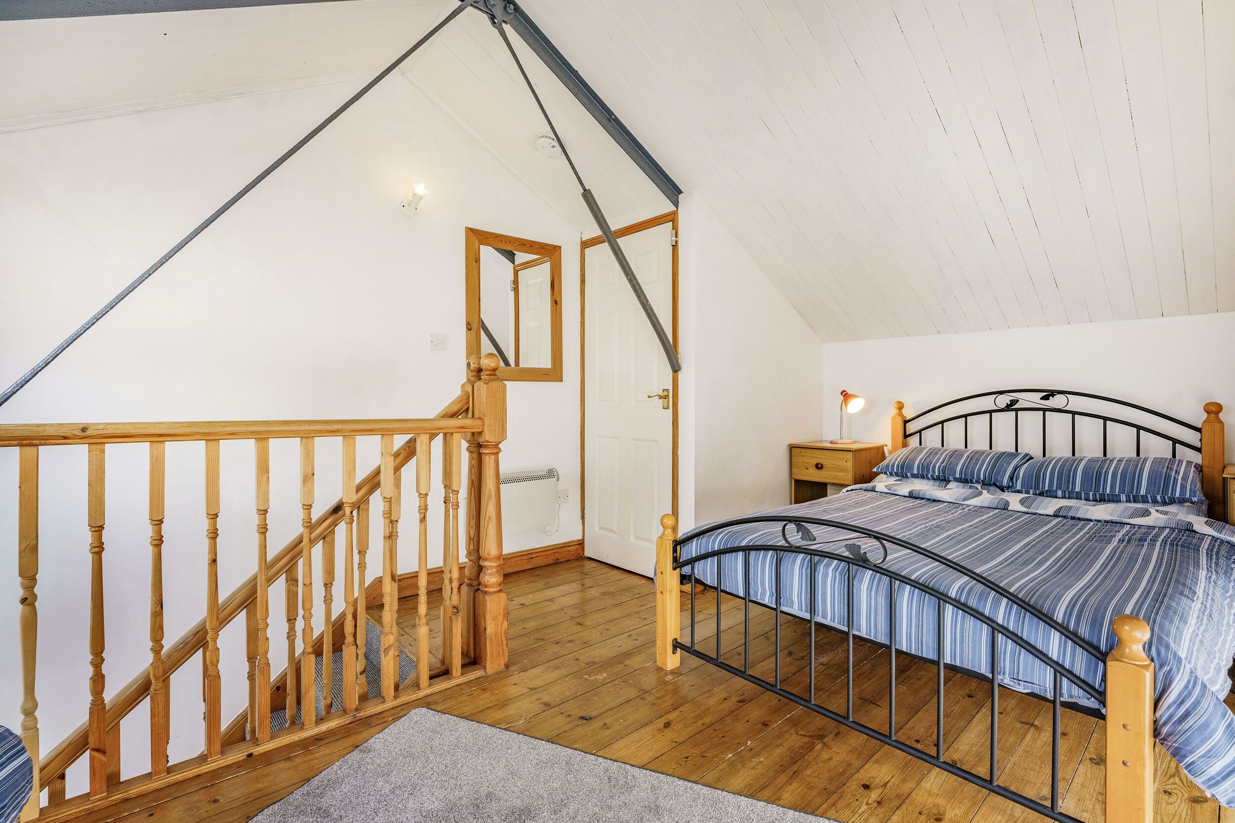 A bedroom with a wooden staircase, a metal bed frame, and a white ceiling.