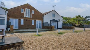A two-story house with a brick exterior and white trim, a front porch, and a gravel driveway. - West Sea View No 4 (Yarmouth)