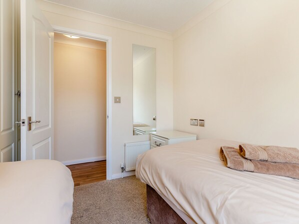 Une chambre à coucher avec un lit, une table de chevet, une commode et un miroir.