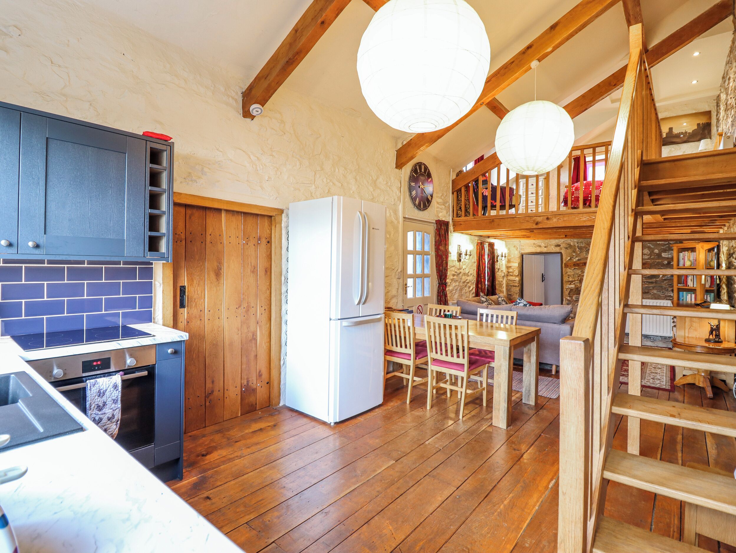 Una cocina rústica con vigas de madera, un refrigerador blanco y un comedor con sillas y mesa de madera.