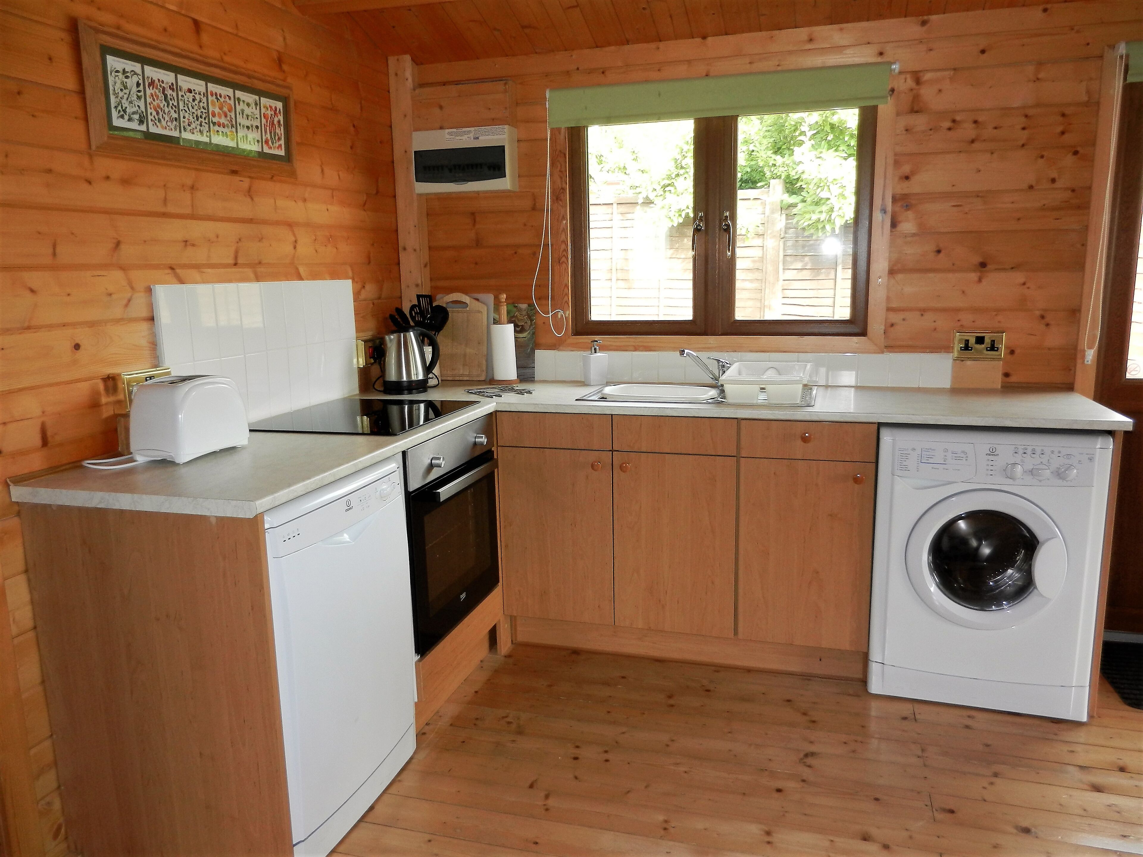 Une cuisine compacte avec des murs en bois, un lave-vaisselle encastré, une cuisinière et un évier.