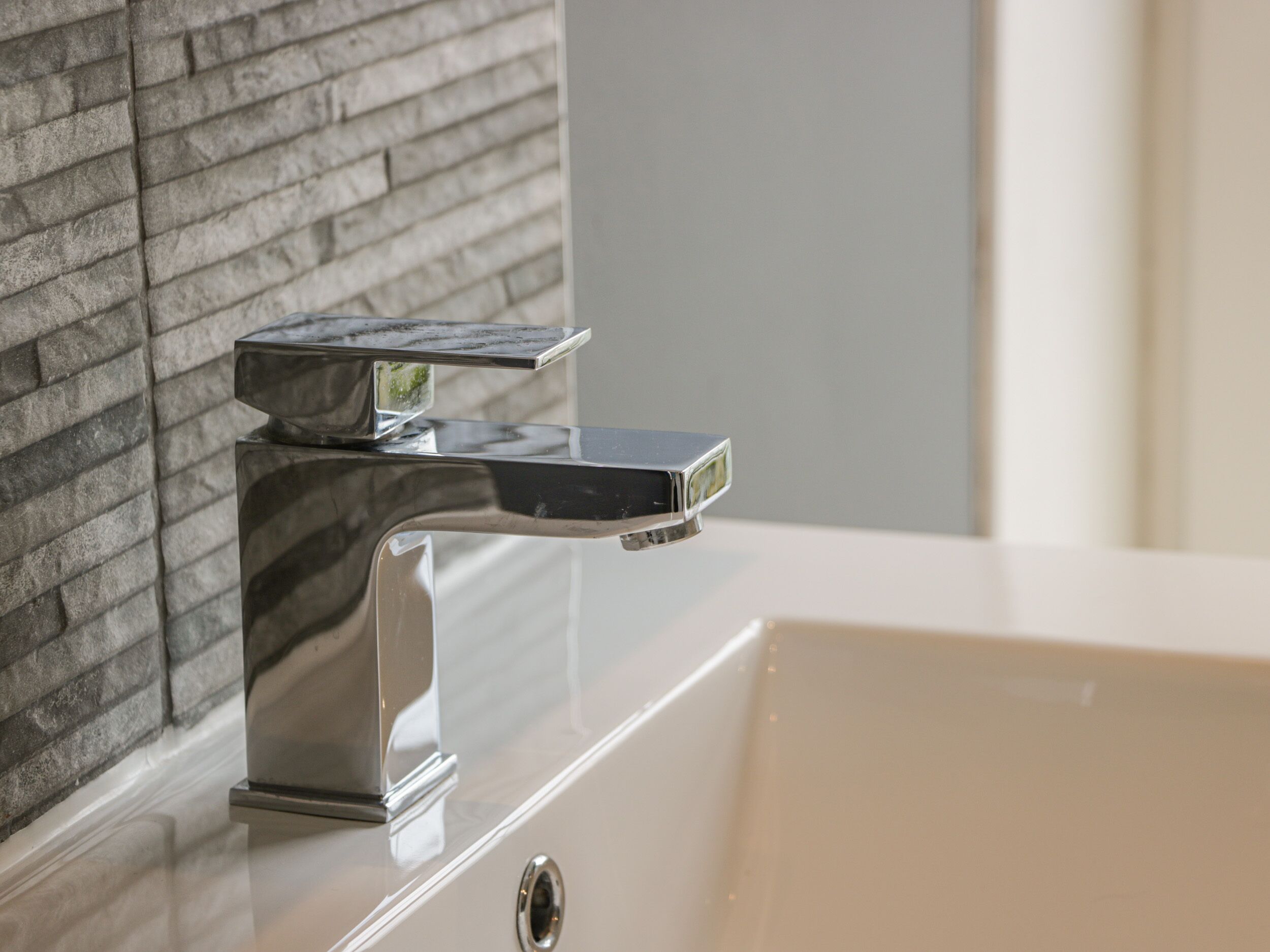 A modern bathroom with a chrome faucet and a white sink.