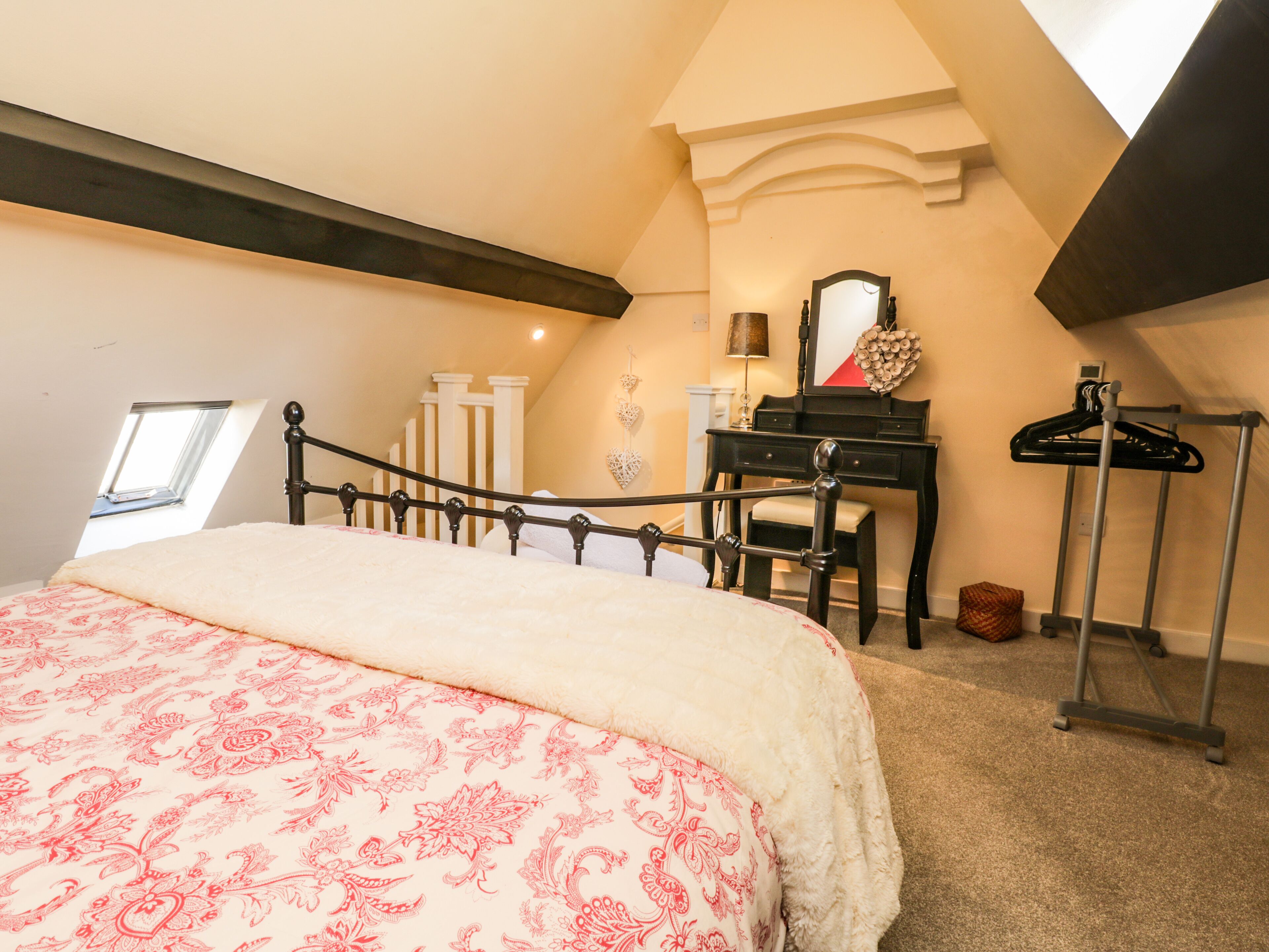 A bedroom with a bed, a dresser, a mirror, a lamp, and a coat rack.