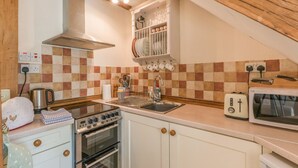 A compact kitchen with a stove, oven, sink, and microwave. - Old Town Cottage (Ludlow)