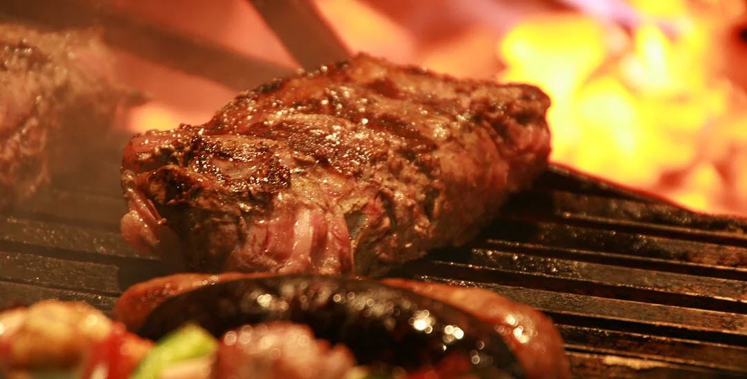A steak being grilled on a barbecue.