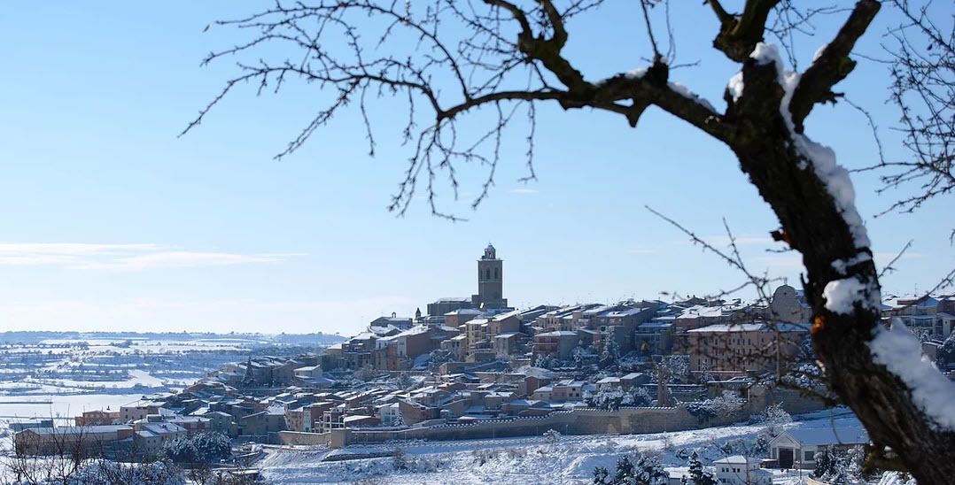 Un pueblo cubierto de nieve con edificios históricos y una torre destacada.
