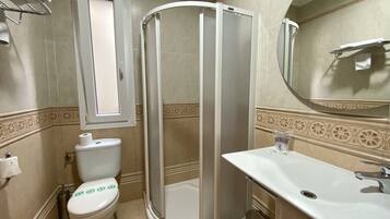 Een badkamer met toilet, douchecabine, wastafel en spiegel.
