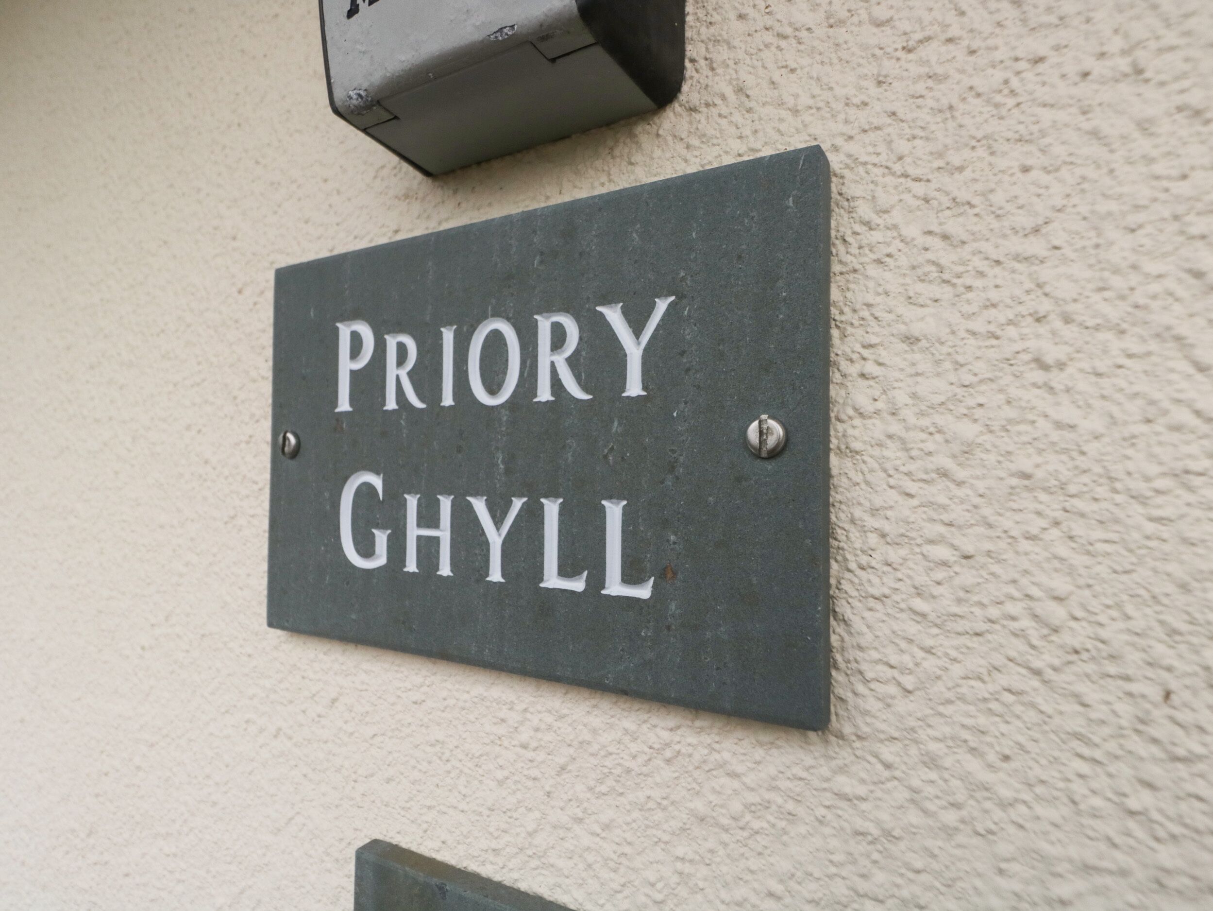 A sign with the name "PRIORY GHYL" mounted on a wall.