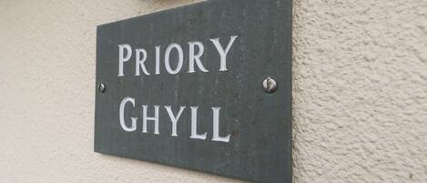 A sign with the name "PRIORY GHYL" mounted on a wall.