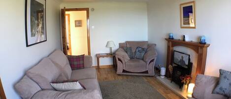 A living room with two sofas, a small table, a fireplace, and a door leading to another room.