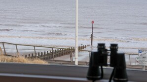 A view of the sea from a window with binoculars in the foreground. - Sea View House (Hornsea)