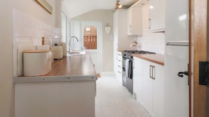 A modern kitchen with white cabinets, a wooden countertop, and a built-in oven. - Sea View House (Hornsea)