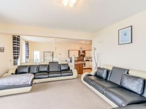 Relax in this stylish living room with two comfortable sofas, a glass coffee table, and a large window with striped curtains.