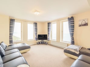 Relax in this comfortable living room with a large flat-screen TV, two sofas, and a carpeted floor.