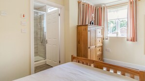 Un dormitorio con cama, armario de madera, armario con ducha y ventana con cortinas.