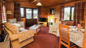 A cozy cabin interior with a sofa, two chairs, a small table, and a television. - Hawthorne Lodge (Saltburn-by-the-Sea)