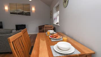 A dining area with a wooden table, chairs, and a breakfast setting including croissants and orange juice.