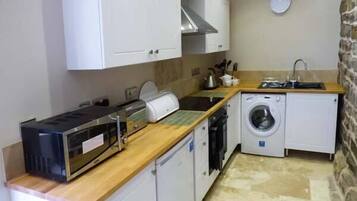 A compact kitchen with a microwave, toaster, sink, and washing machine.