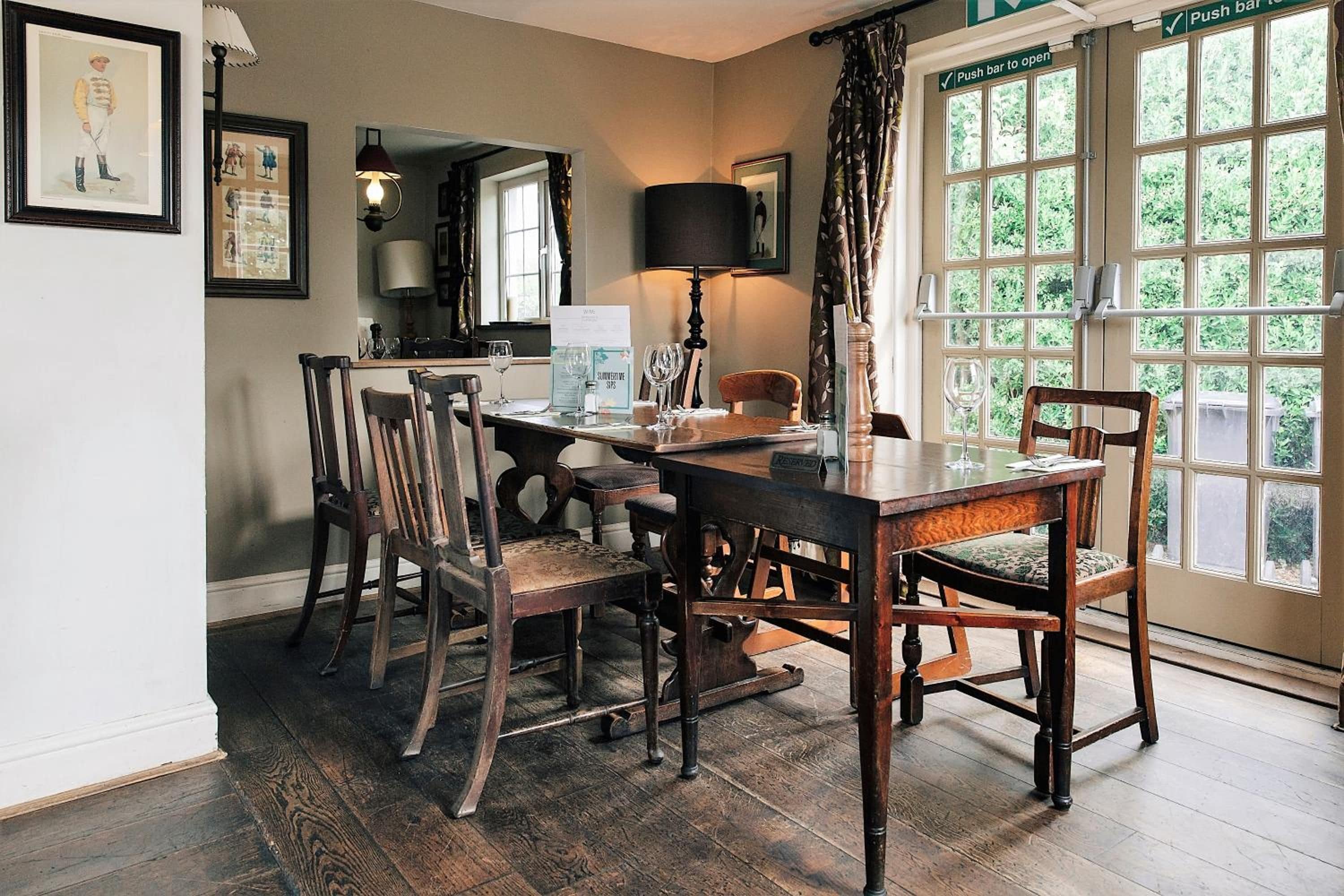 A dining area with a wooden table, chairs, and a window with a view of greenery.