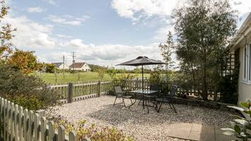 An outdoor patio with a table and chairs, a wooden fence, and a view of houses in the background.