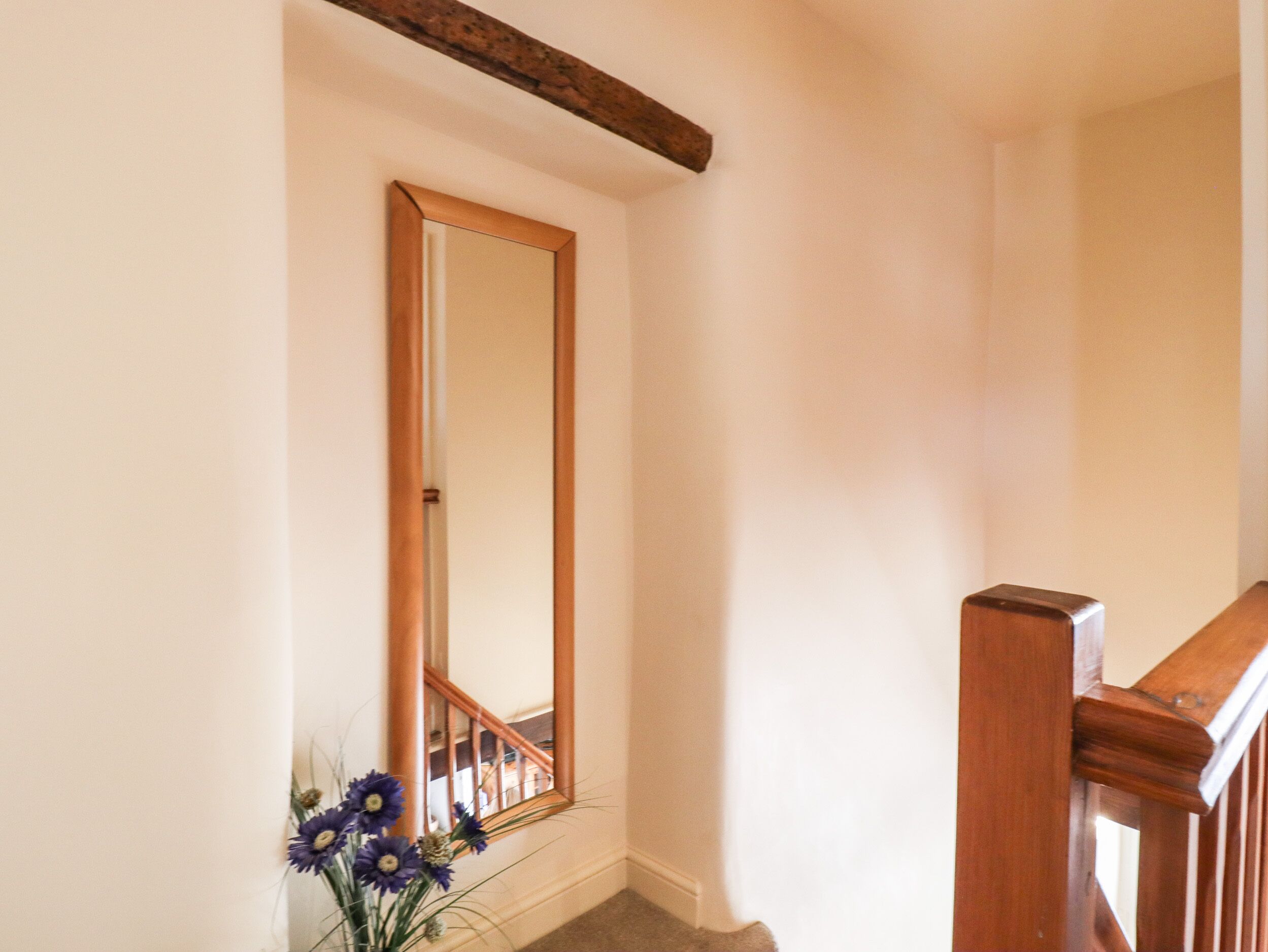 A staircase with a wooden handrail and a mirror on the wall.