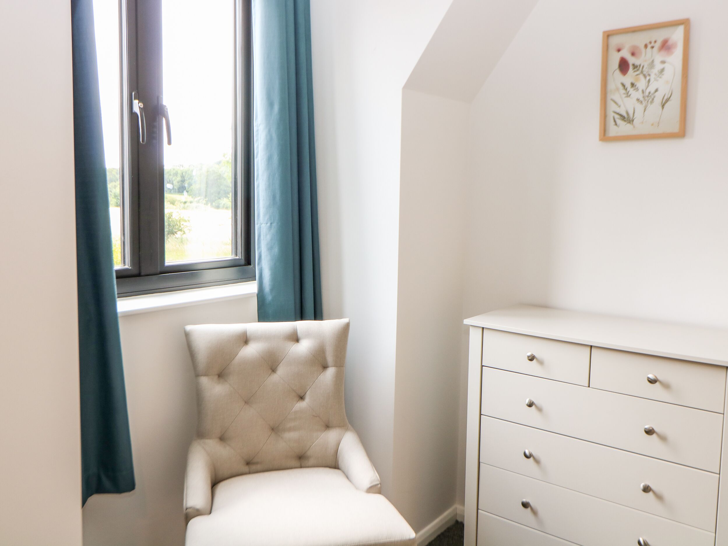 A corner room with a window, a chair, and a dresser.