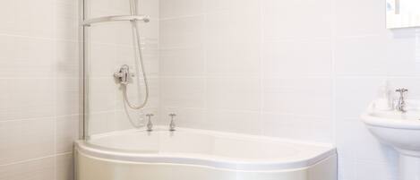 A modern bathroom with a freestanding bathtub, a showerhead, and a sink.